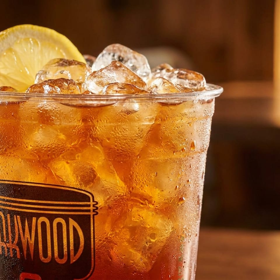 Iced tea in a plastic cup with a lemon slice and ice, showing the Oakwood logo.